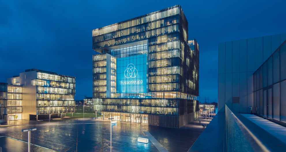 Moderne BÃ¼rogebÃ¤ude bei Nacht mit beleuchteten Fenstern und einer groÃŸen Glasfassade, die