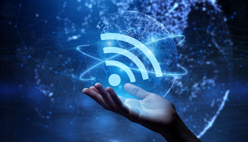 Hand, die ein leuchtendes WLAN-Symbol hÃ¤lt, umgeben von digitalen Netzwerkelementen auf blauem Hintergrund.