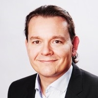 Professionelles Business-PortrÃ¤t, das eine Person in einem formellen Sakko und einem Hemd mit Kragen vor einem klaren weiÃŸen Hintergrund zeigt und damit unternehmerische ProfessionalitÃ¤t sowie ein FÃ¼hrungsprofil vermittelt.