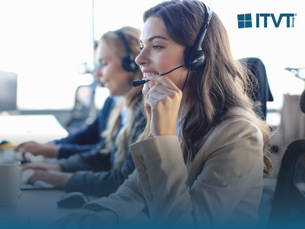 Drei Callcenter-Mitarbeiter mit Headsets, im Vordergrund eine lÃ¤chelnde junge Frau, arbeiten an Computern. Das Logo der ITVT Group erscheint in der oberen rechten Ecke.
