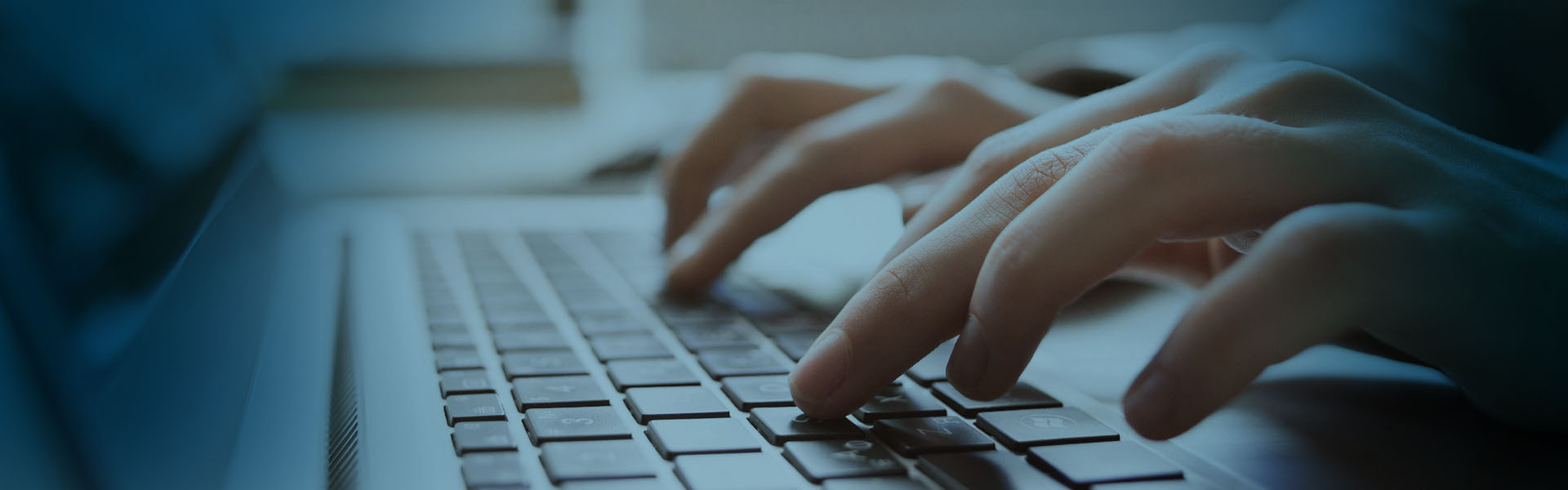 Eine Nahaufnahme von HÃ¤nden, die auf einer Laptop-Tastatur tippen, mit einem sanften blauen LichtÃ¼berzug, der eine konzentrierte und professionelle AtmosphÃ¤re schafft.