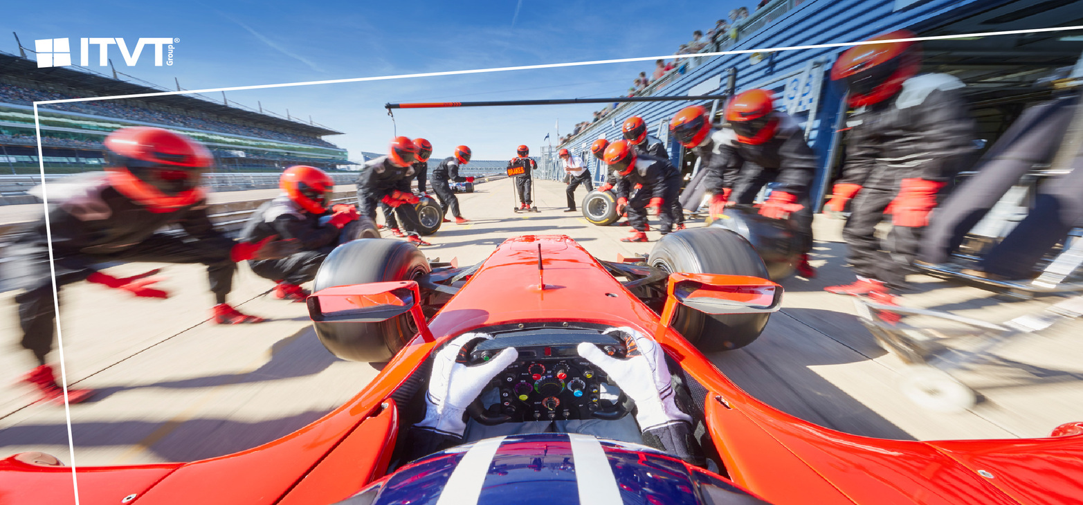 Ein Bild der Marke ITVT, das einen Hochleistungs-Rennwagen wÃ¤hrend eines Boxenstopps aus der Perspektive des Fahrer-Cockpits zeigt, umgeben von einer professionellen Boxencrew und AusrÃ¼stung, als Symbol fÃ¼r Geschwindigkeit, PrÃ¤zision, Teamarbeit und operative Exzellenz.